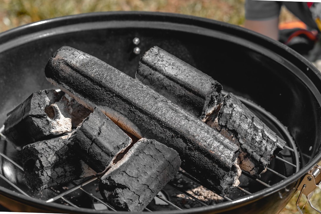 Dense hardwood charcoal burning down to grey-ashed cooking coals on a kettle grill