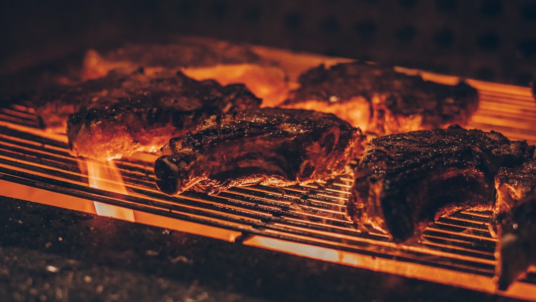 Steaks searing over glowing hardwood charcoal at high heat on the grill grate