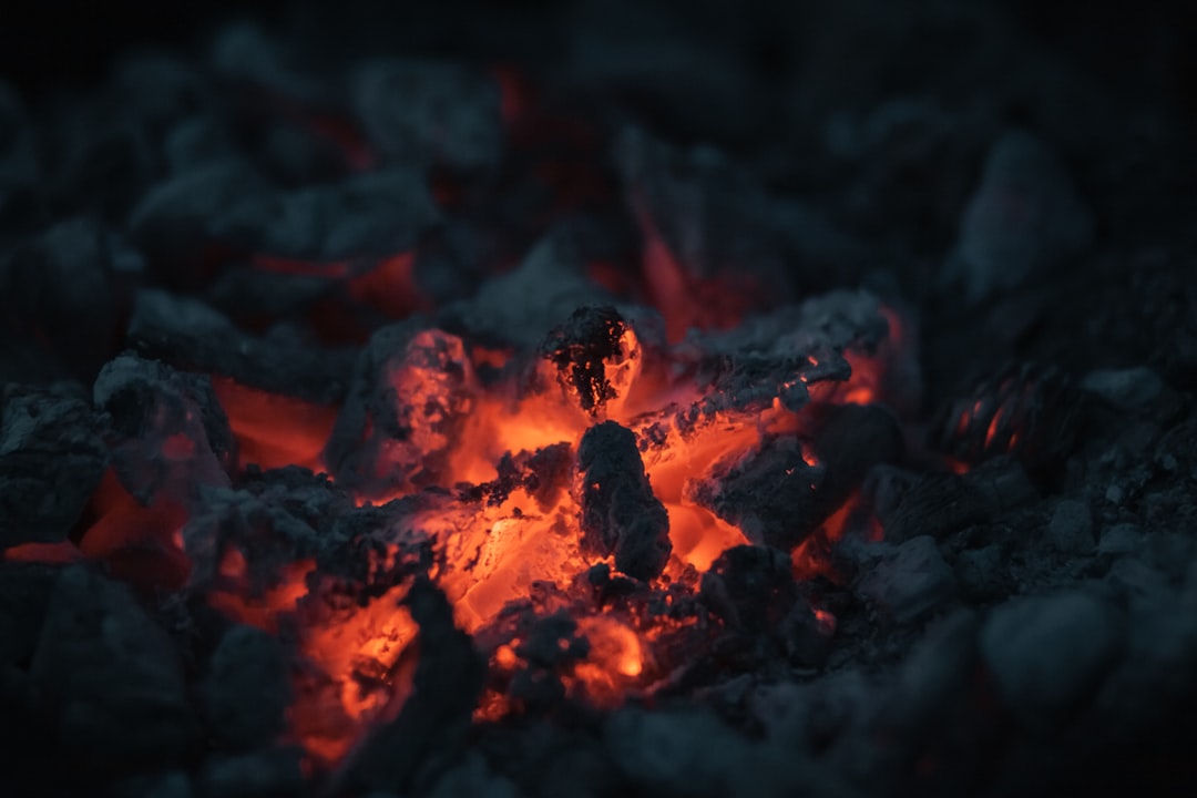 Glowing lump hardwood charcoal in a grill, the high-heat live fire that defines hardwood charcoal vs briquettes