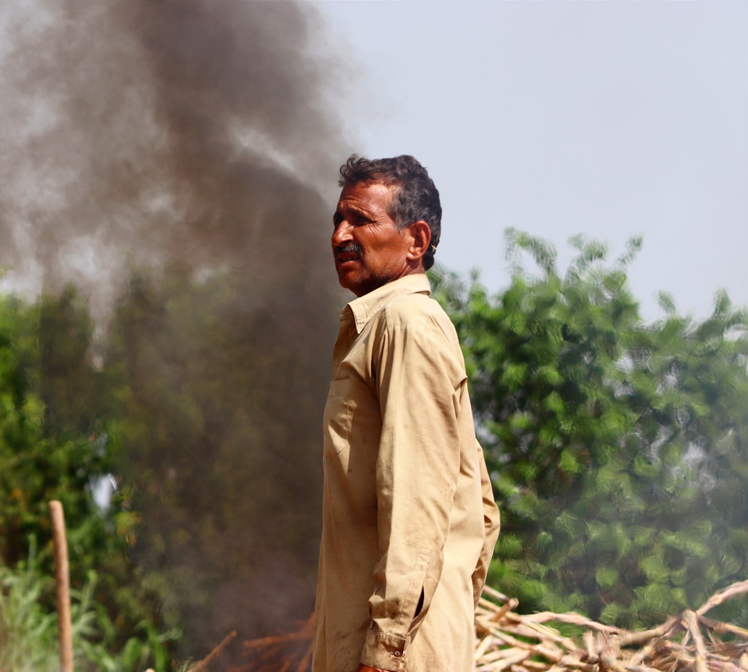 A worker beside a smoking burn, the stage that decides how dense the charcoal comes out