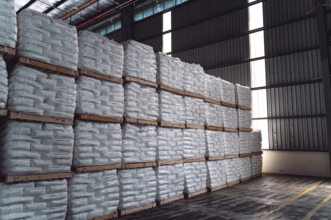 Sacks stacked on pallets in covered storage, kept off the ground where humidity would otherwise creep back into the charcoal